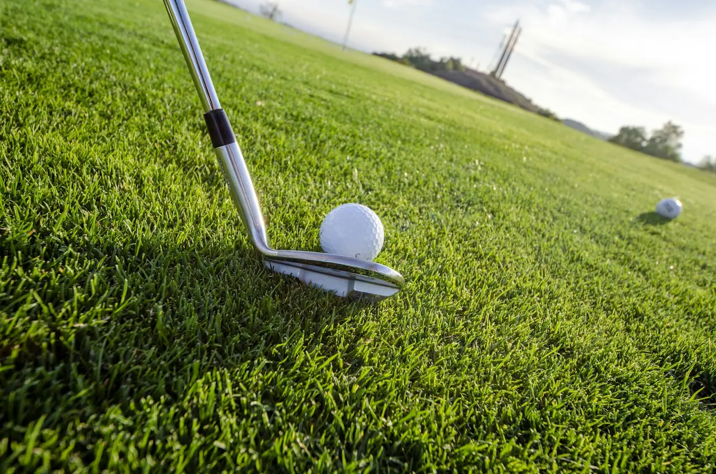 Bastón de golf junto a la pelota sobre el pasto