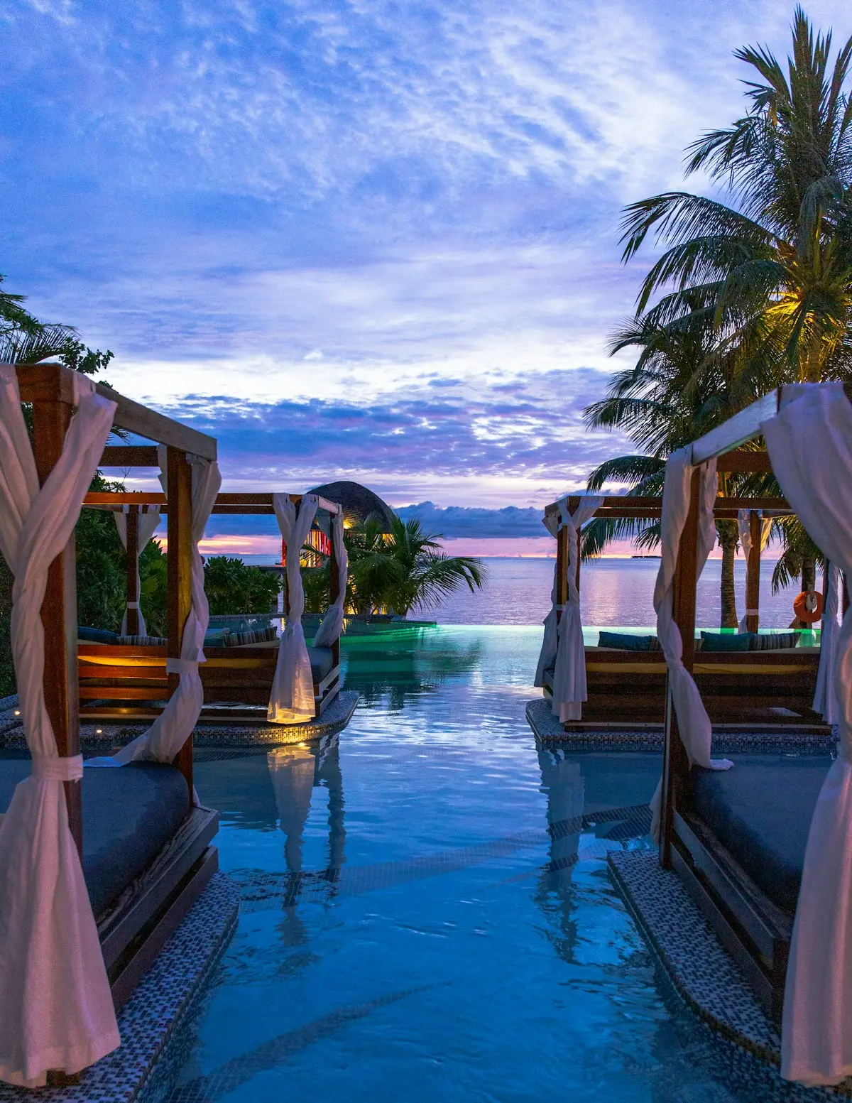 Alberca privada de suite al atardecer, con camastros y cortinas